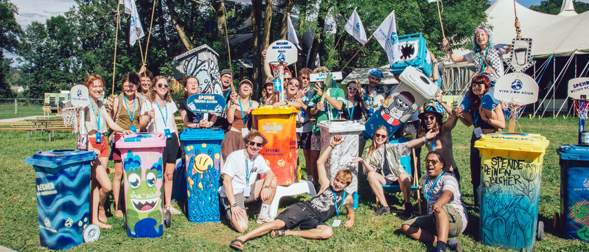 A group with colorful painted garbage cans and Viva Con Agua signs and flags