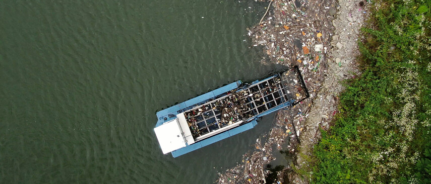 A cleanup boat cleans a beach full of garbage